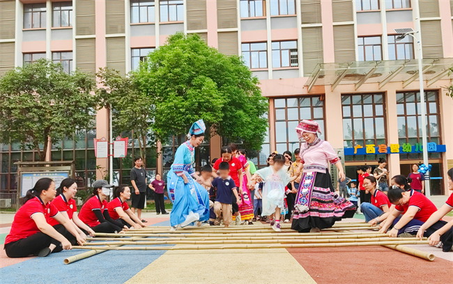 图为幼儿与家长、老师跳竹竿舞